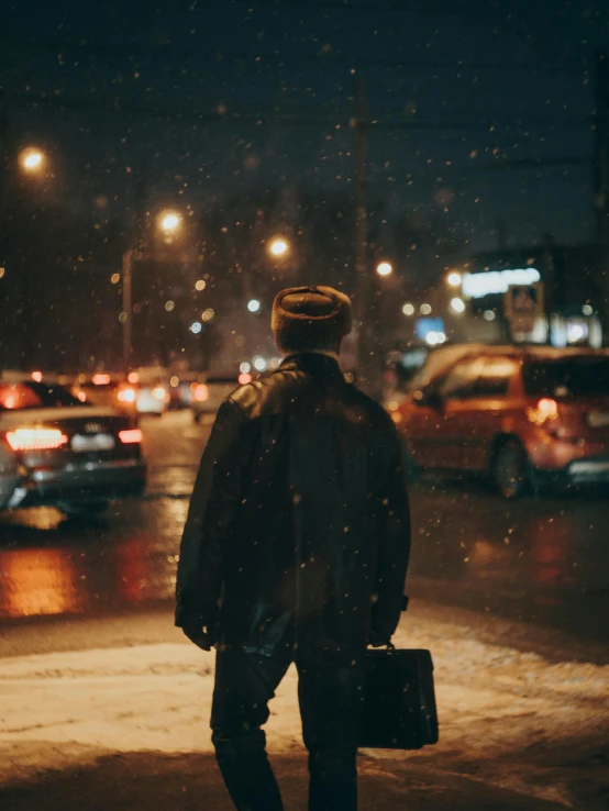 man standing on side walk at night holding an open suitcase