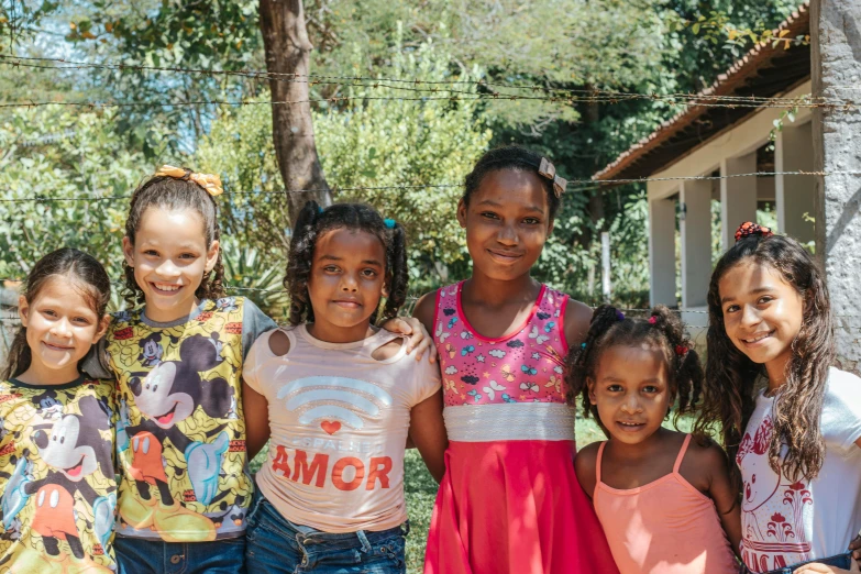 six girls are standing together outside by a fence