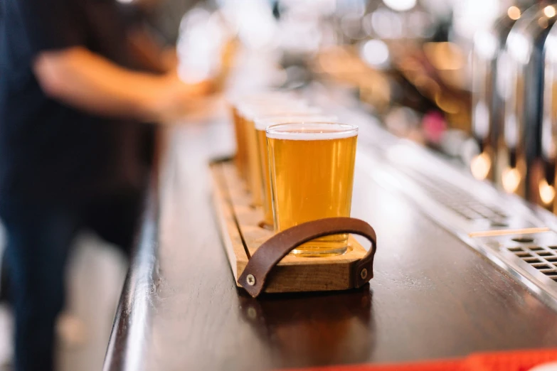 the person stands near an empty glass next to a long row of beer