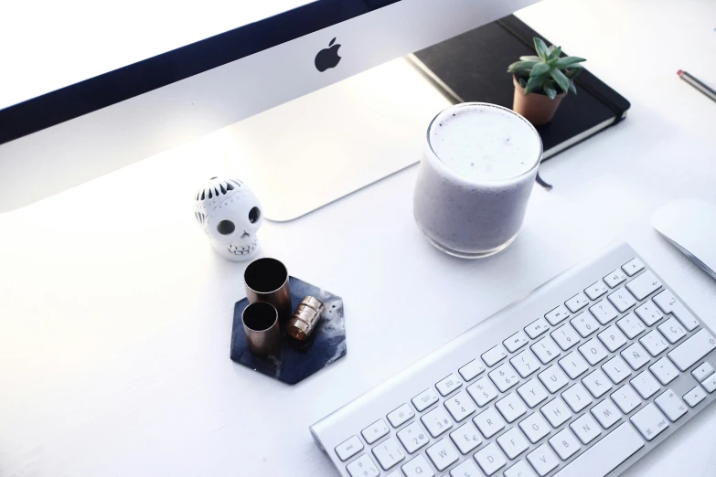 a computer, coffee mug and keyboard sit on a desk