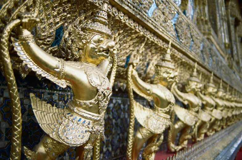 a row of statues with gold paint on them