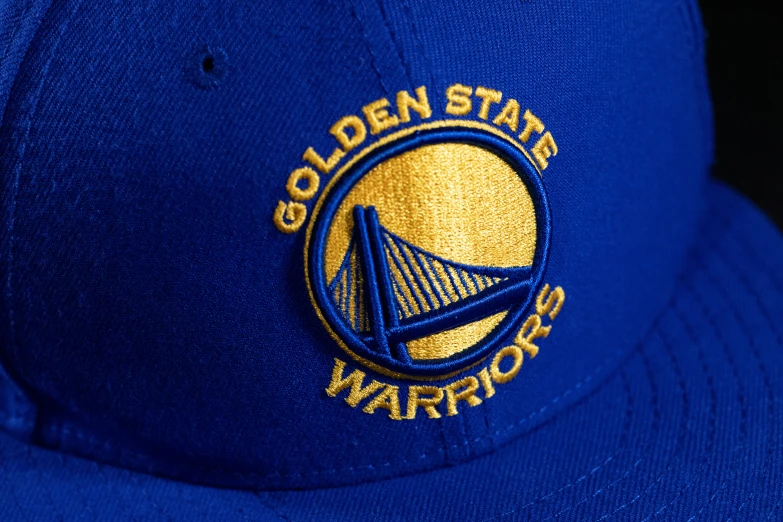 a golden state warriors hat sits on a wooden surface