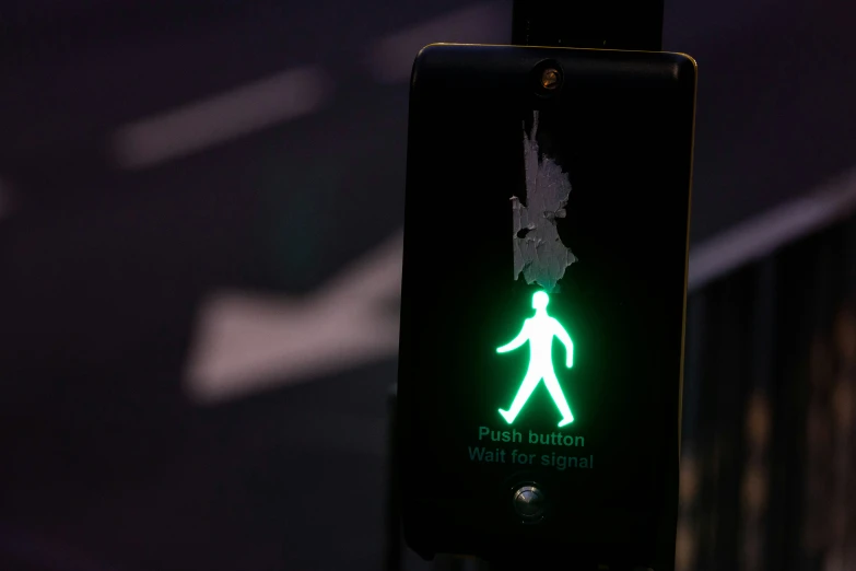 a green pedestrian walk light sign is illuminated in the dark