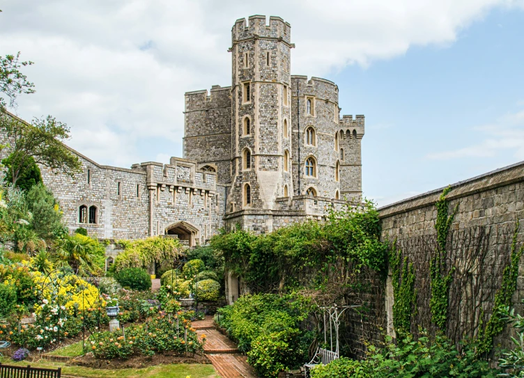 a walkway leading through the garden to a building with a massive tower