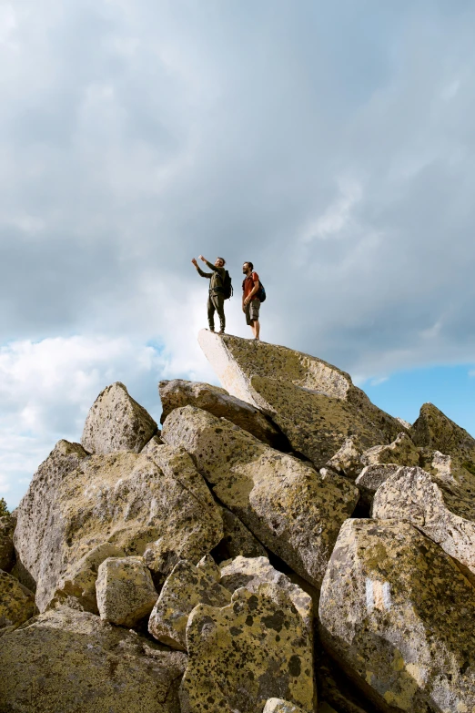 two people standing on top of a rocky hill