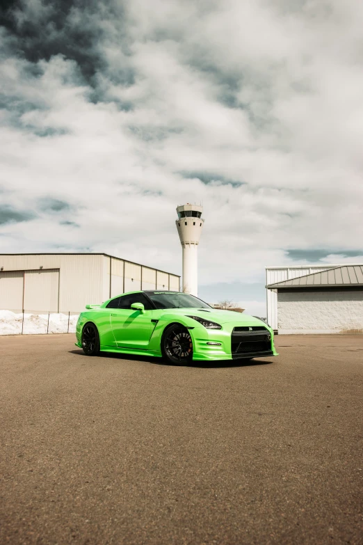 a green sports car is parked outside an airport