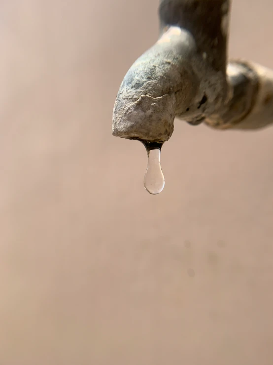 a water drop that is hanging off the side of a fountain