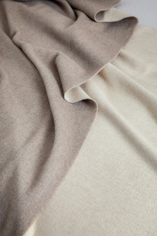 a bed with a blanket that has light brown colored material