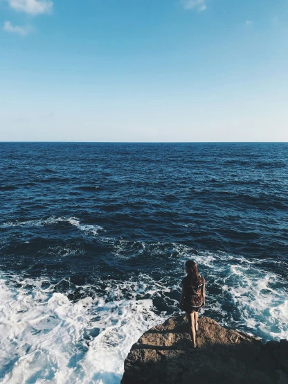 the woman looks out over the ocean as she stands on a cliff