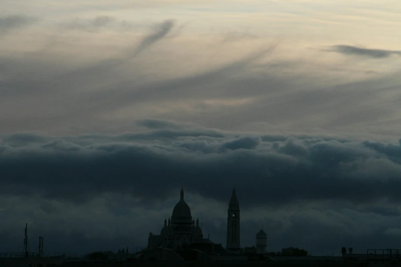 a dark picture of some clouds over a city