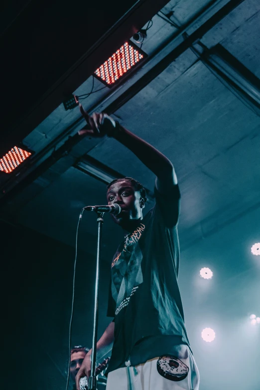 a man on stage holding his arm up and singing into a microphone