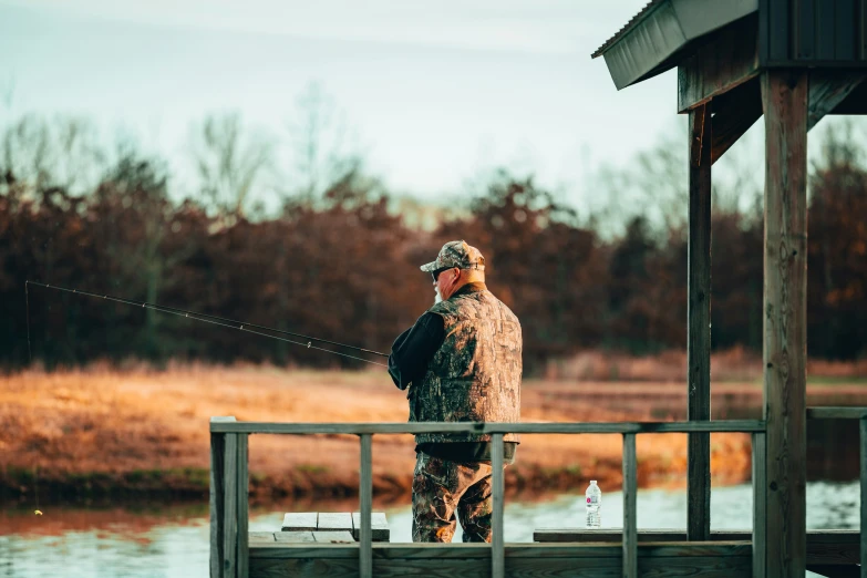 a man standing on top of a wooden dock next to a lake