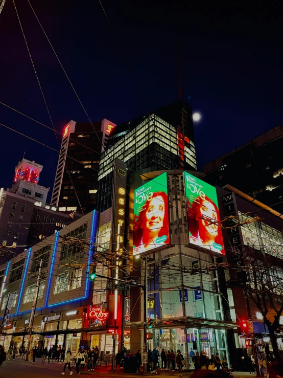 an intersection at night with lights and signs on buildings