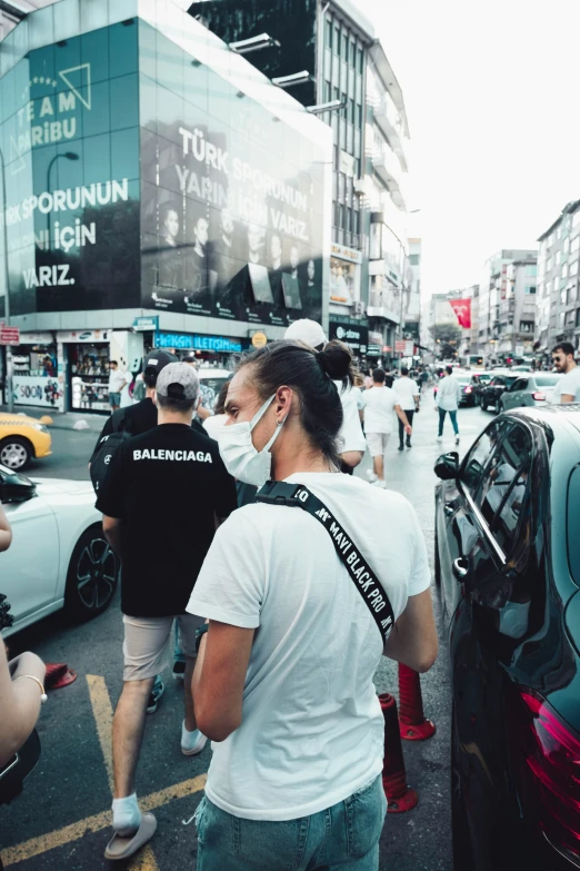 a man standing in the middle of a busy city street wearing a face mask