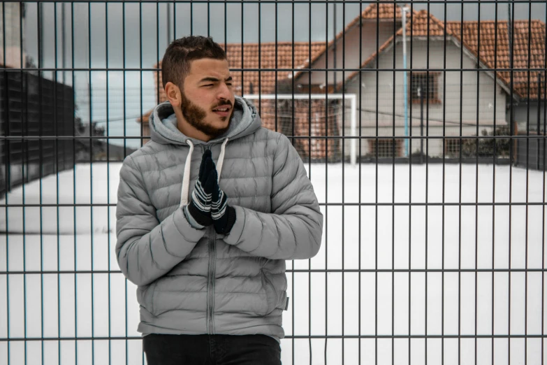 a man in gray jacket looking through fence