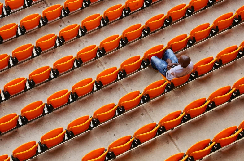 someone laying on the floor with a bunch of orange chairs