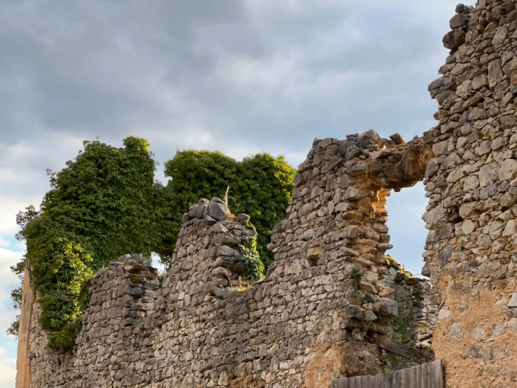 a castle ruins in front of trees and clouds