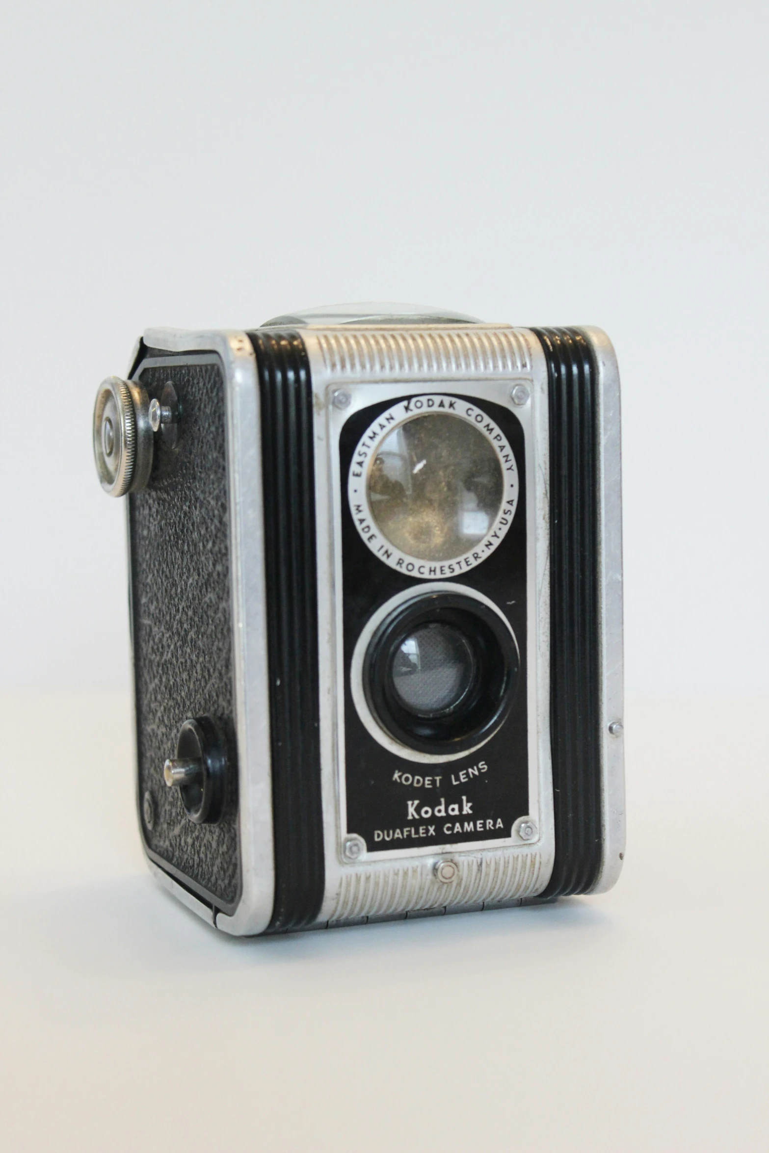 an old fashioned camera sitting on top of a white surface