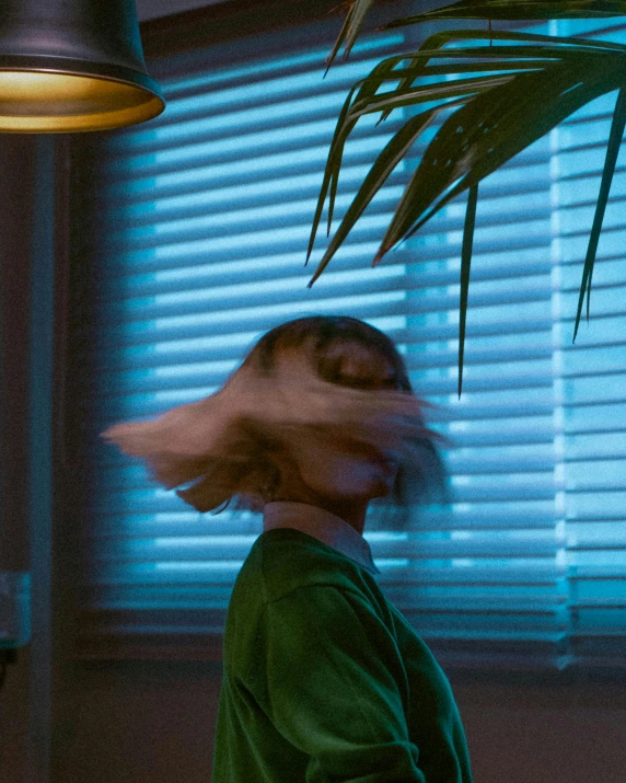 woman in green dress standing by a plant under a blue light