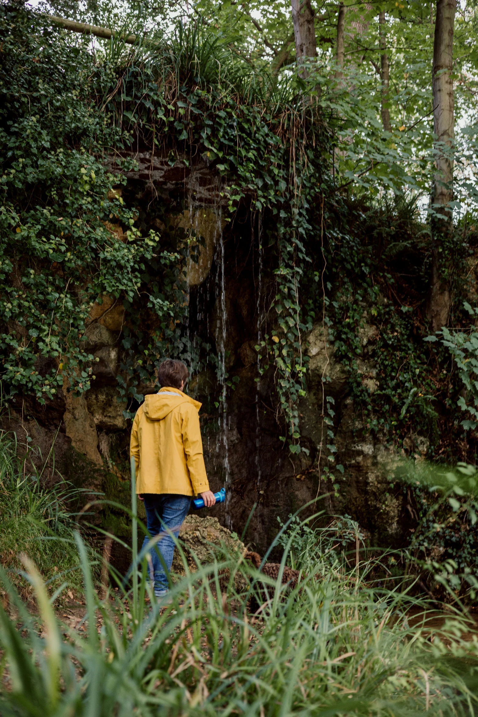 a man is looking down at some water coming out of the cave