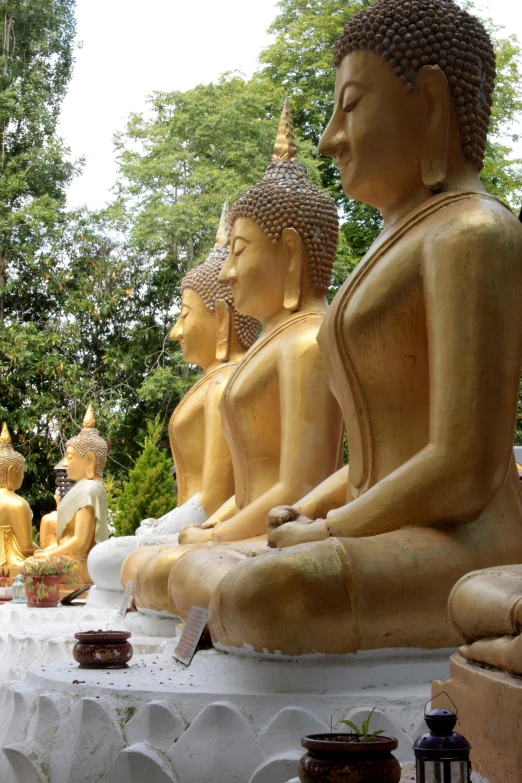 a large buddha statue sitting outside next to other buddhist statues