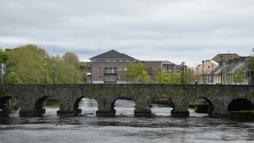 a stone bridge crosses a river in an old city