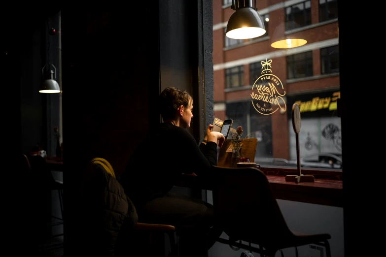 a man in a black shirt sits at a table and drinks