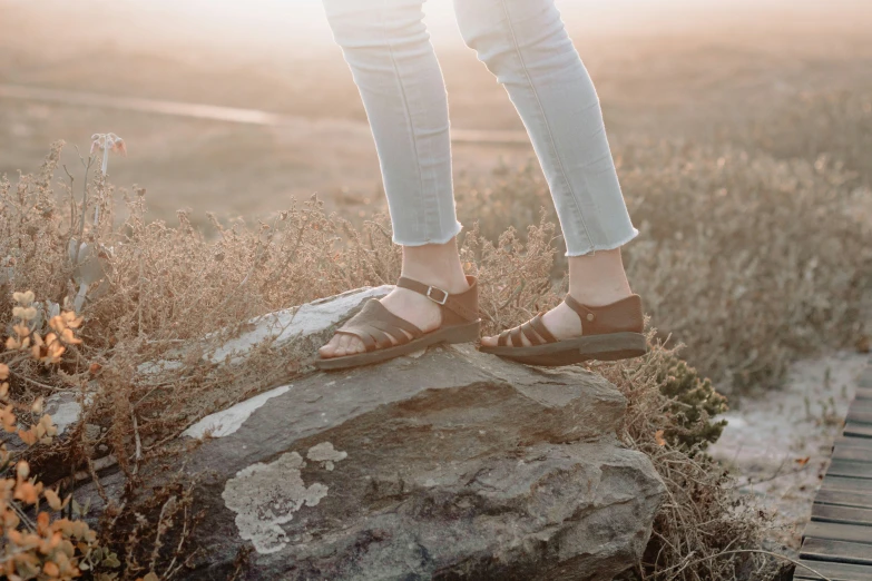 a woman stands on top of a large rock