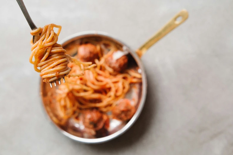 a fork full of pasta with meatballs in it