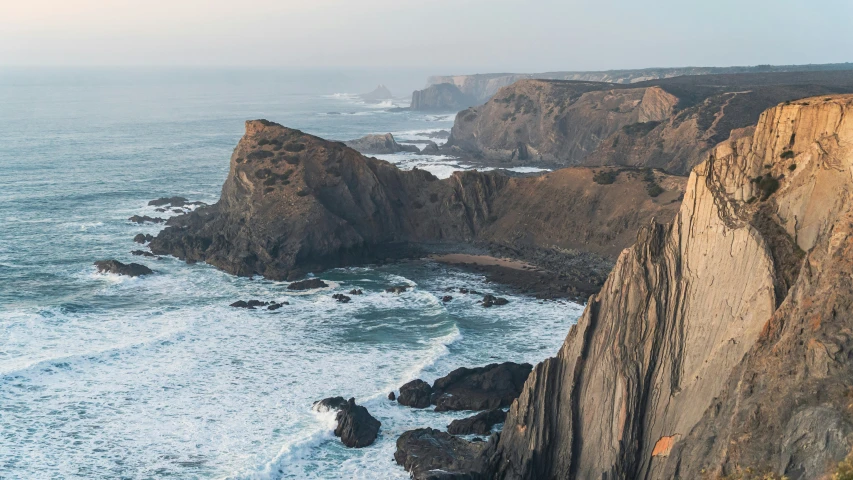 two rocks off the edge of a cliff by a body of water