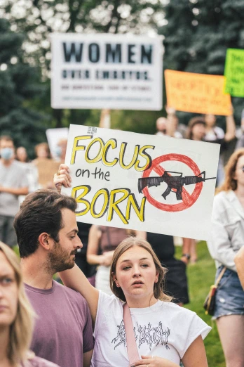 people stand in a protest with a gun sign in front of them