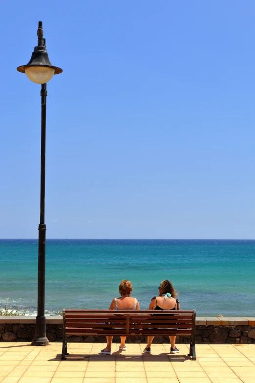 two people sitting on top of a bench