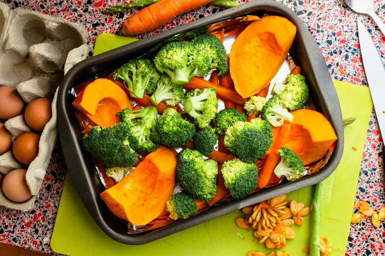 a tray filled with carrots and broccoli next to eggs