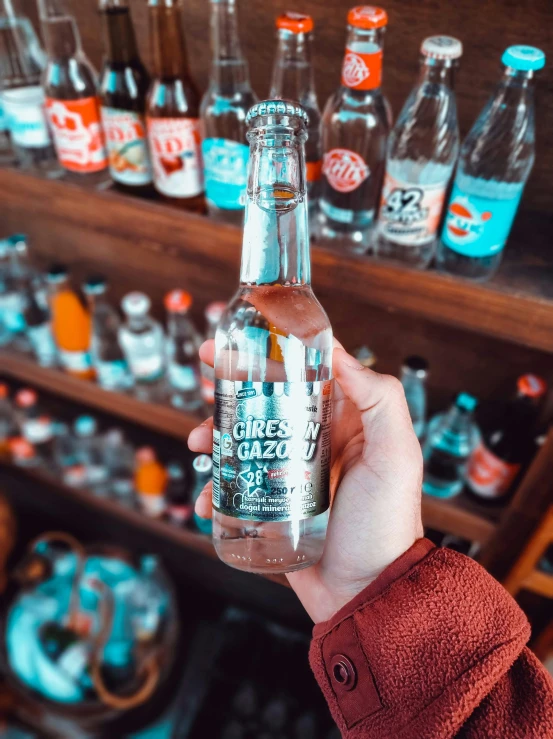 a person holding a bottle in front of bottles