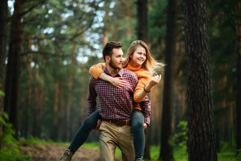 a man carrying a woman while walking through a forest