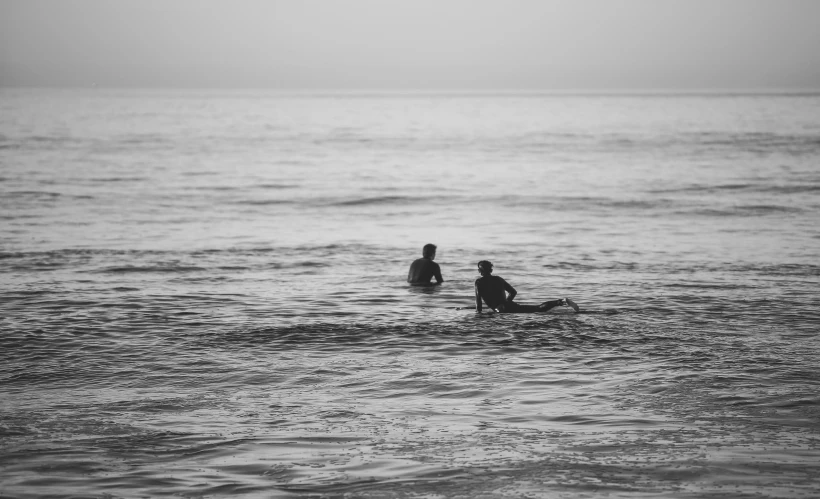 two people sitting on surfboards in the ocean