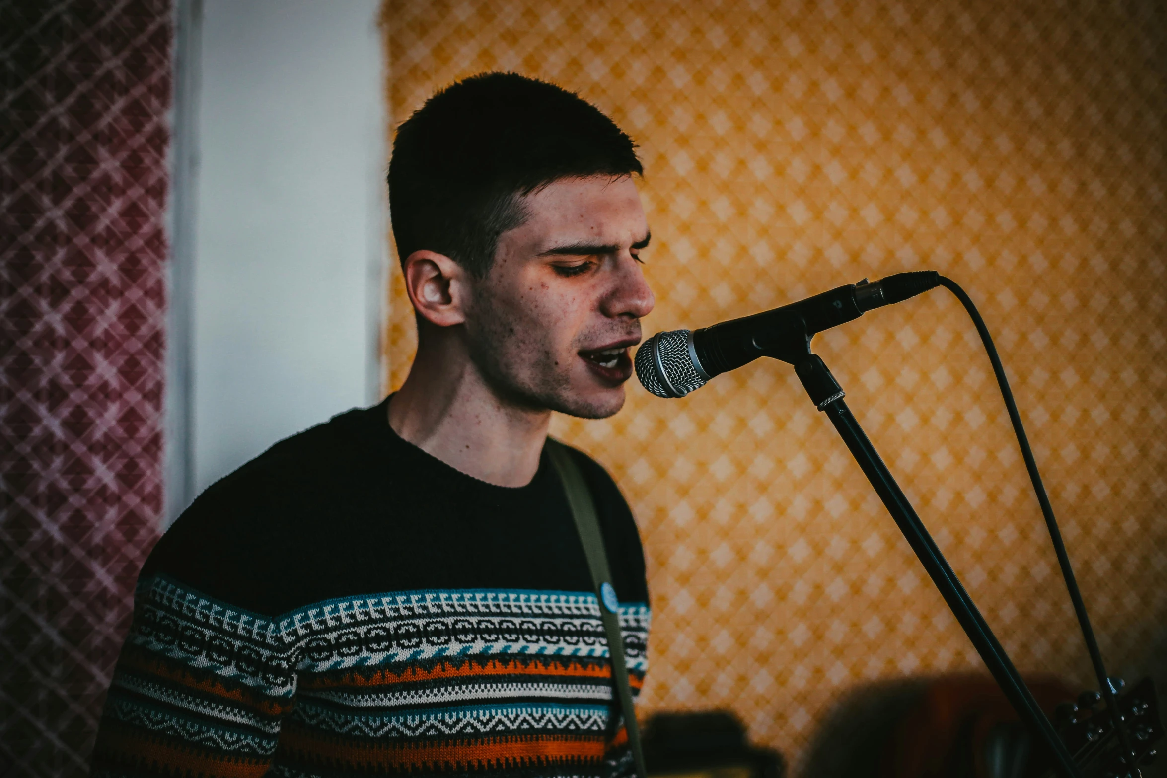 a man with an open mouth sings into a microphone