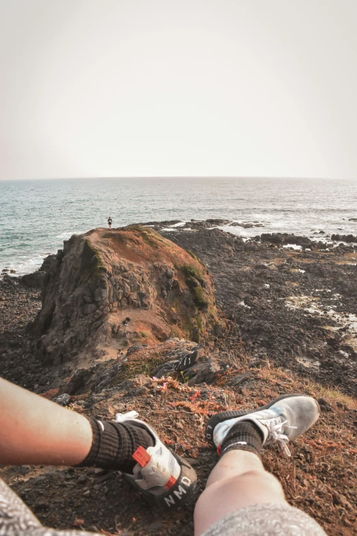 a person resting on a rock next to the ocean