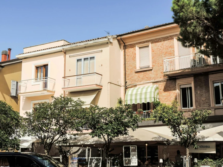 three large buildings, one with windows above the other and awnings in front