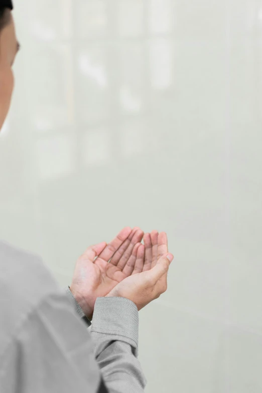 a woman is standing in front of the wall with her hands in prayer