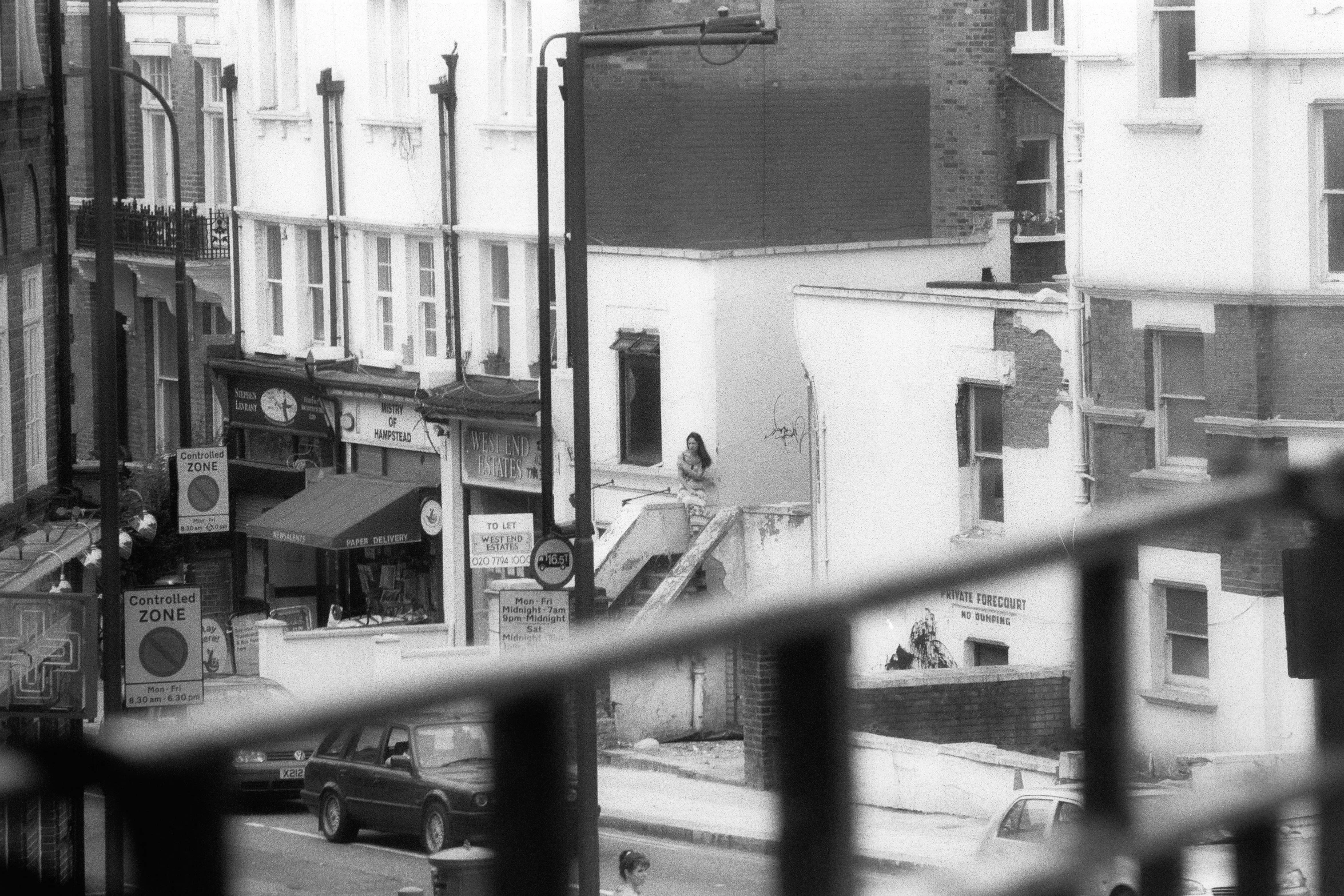 a black and white pograph of people on a street corner