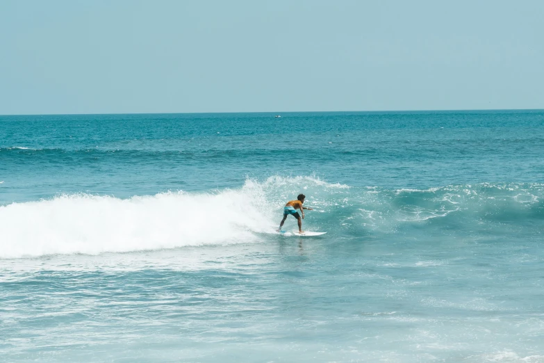 a surfer stands on his board and crests a wave in the ocean