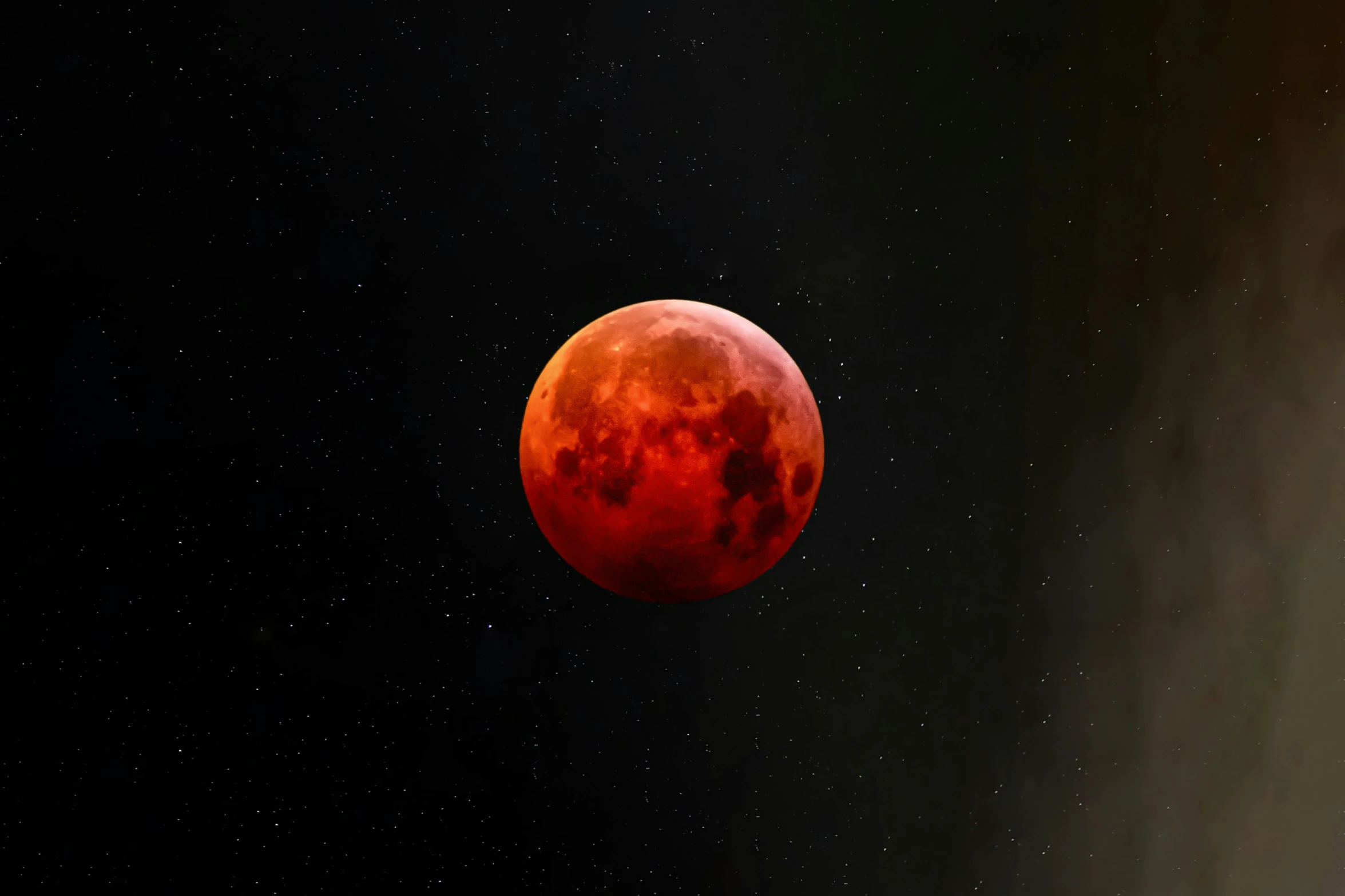 a red moon rising with some stars behind it