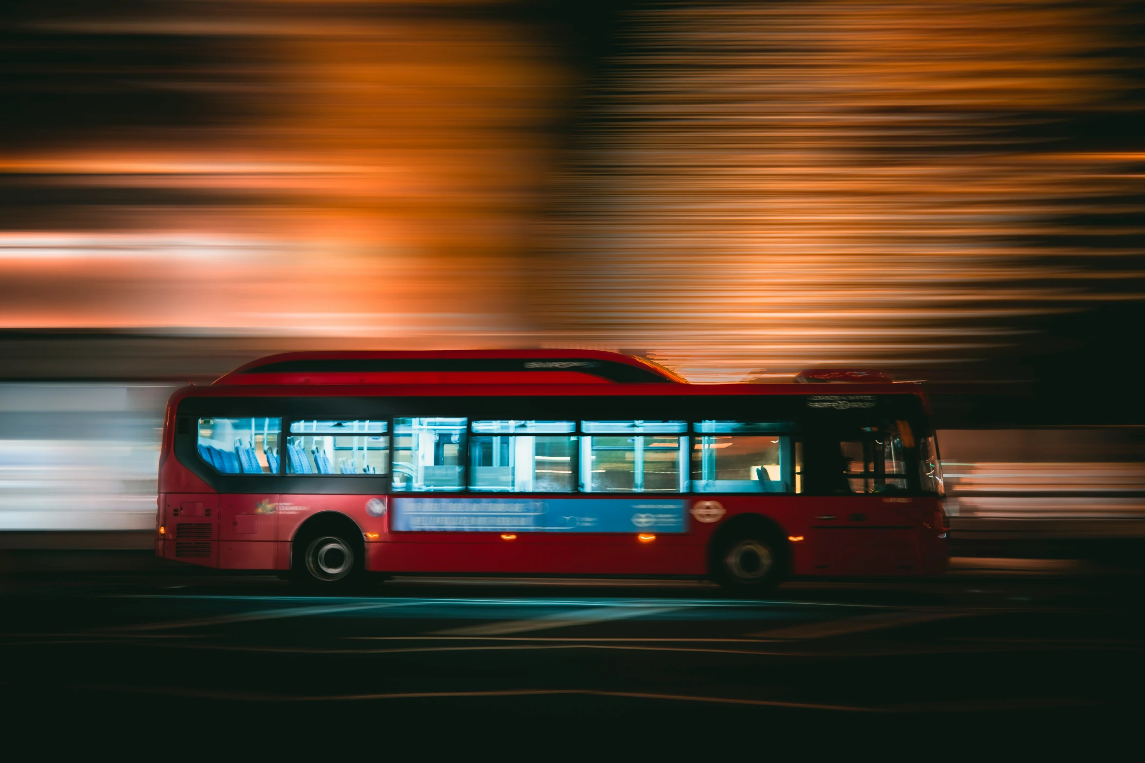 red bus in motion on a street at night