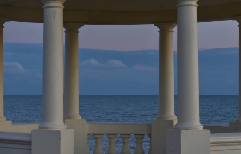 an umbrella sits on top of the roof of a gazebo by the ocean