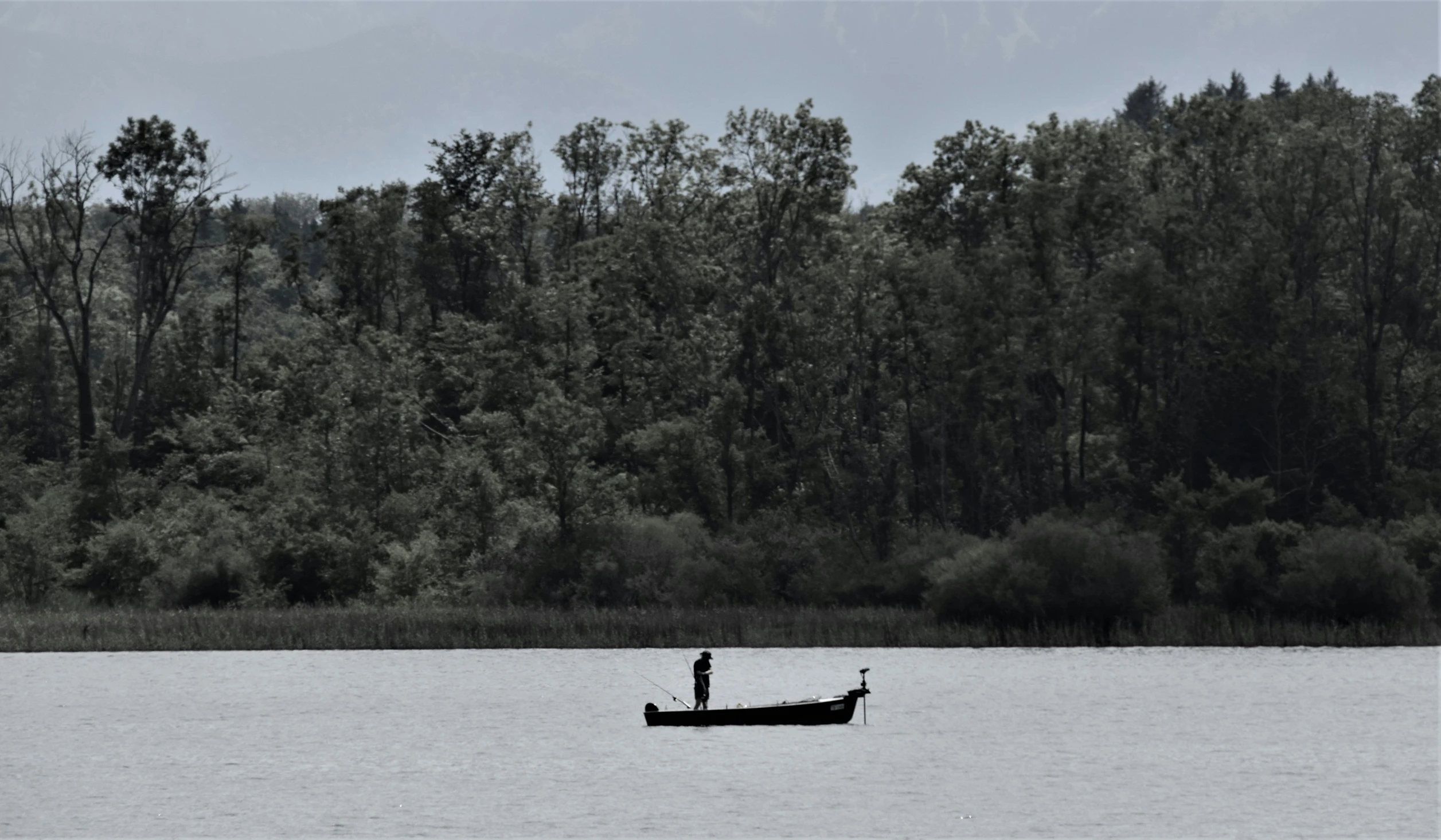 a black and white po of a person fishing in a boat on a river