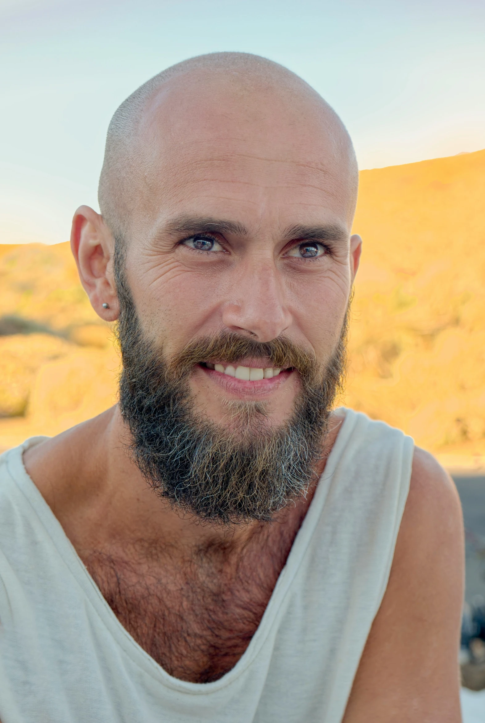 a balding guy with blue eyes wearing white tank tops