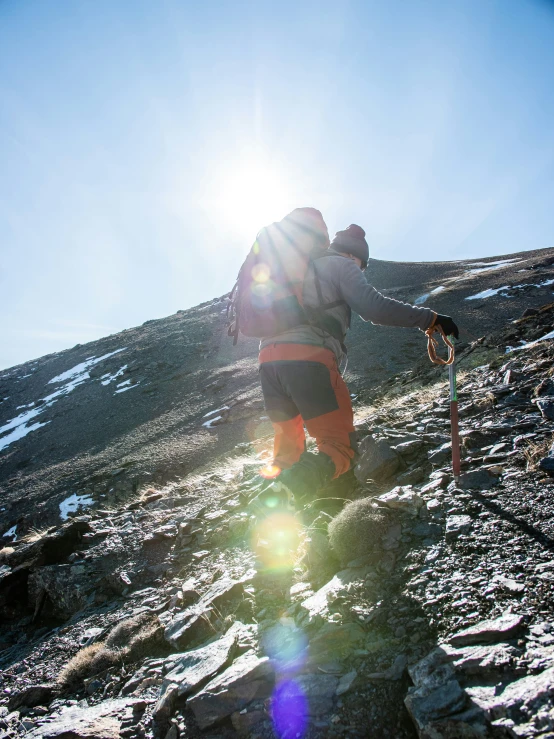 a skier with an orange jacket walking up a hill