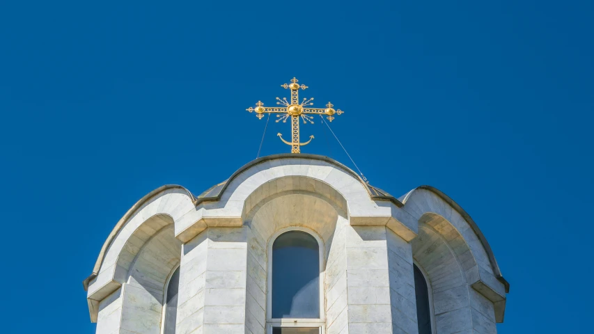 the top of a church steeple with gold crosses on it