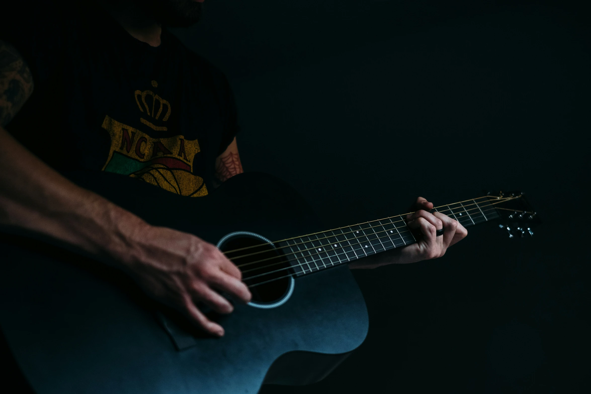 a person holding a guitar on a dark background